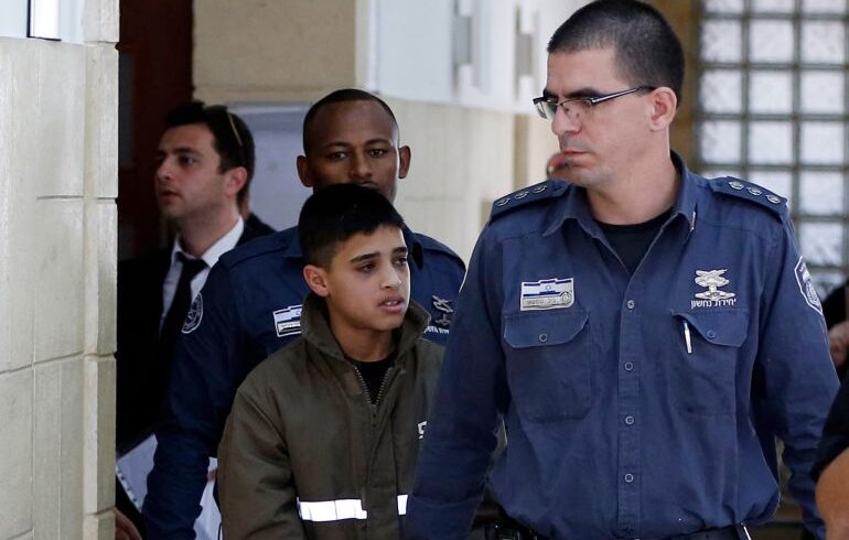 Ahmed Manasra (C), a 13-year old Palestinian accused of taking part in the stabbing of two Israelis earlier this month, is escorted by Israeli security during a hearing at a Jerusalem court on October 30, 2015. Manasra was charged this morning with the illegal possession of a knife and attempted murder. AFP PHOTO / AHMAD GHARABLI (Photo by AHMAD GHARABLI / AFP)