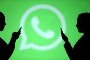 Silhouettes of mobile users are seen next to a screen projection of Whatsapp logo in this picture illustration taken March 28, 2018. REUTERS/Dado Ruvic/Illustration